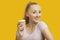 Portrait of beautiful young woman holding disposable cup over yellow background