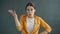 Portrait of beautiful young woman knocking on head showing fool gesture on gray background