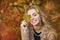 Portrait of beautiful young woman with a leaf in a hand in autumn