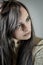 Portrait of a beautiful young woman with long brown hair absorbed and serious looking to the side