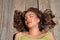 Portrait of beautiful young woman with long brown hair and cinnamon skin, lying on a wooden bench with her eyes closed. Beauty