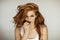 Portrait of a beautiful young woman with long red curly hair and freckles