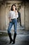 Portrait of beautiful young woman with modern outfit, leather jacket, jeans, white blouse and black boots