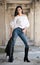 Portrait of beautiful young woman with modern outfit, leather jacket, jeans, white blouse and black boots