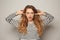 Portrait of beautiful young woman plugging ears on light background