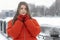 Portrait of beautiful young woman in red warm jacket and mittens in winter outside. Trendy youth warm clothing