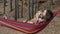Portrait of beautiful young woman relaxing in hammock in autumn forest kissing shiba inu dog