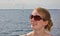 Portrait of a beautiful young woman wearing sunglasses with the sea and a distant sailboat in the background