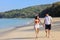 Portrait of beautiful young women and boyfriend asian, wearing rea bikini and stylish white sunglasses walking on the seashore