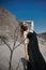 Portrait of a beauty fashion woman in the branches of a dead tree. Girl on the background of sand mountains