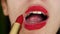 Portrait of beauty girl who ineptly paints lips with bright red lipstick. Macro shot of young woman make up lips applying red lips