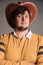 Portrait of big man in a cowboy hat and a yellow shirt. Skeptically young man. The studio shot in the gray wall.