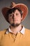 Portrait of big man in a cowboy hat and a yellow shirt. Young man. The studio shot in the gray wall. Neutral facial expression