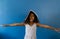 Portrait of biracial schoolgirl with arms outstretched and notebook on head, on blue background