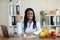 Portrait of black female dietitian showing okay gesture at table with laptop and fresh products in clinic