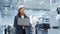 Portrait of a Black Female Engineer in Hard Hat Standing and Using Laptop Computer at Electronic