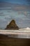 Portrait of black Karekare Beach with the Watchman Rock.