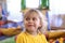 Portrait of a blond boy in a yellow t-shirt. The child smiles and plays in the children`s playroom