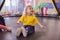 Portrait of a blond boy in a yellow t-shirt. The child smiles and plays in the children`s playroom. The child jumps on the