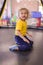 Portrait of a blond boy in a yellow t-shirt. The child smiles and plays in the children`s playroom. The child jumps on the