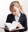 Portrait of blond Caucasian schoolgirl reading textbook