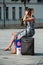 Portrait of blond girl with blue dress and phone waiting with suitcase in front of the train station