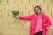 Portrait of blond joyful smiling woman staying near yellow brick wall with pink bouquet of flowerd gift celebration