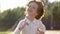 Portrait of blond little cute boy running in summer day and smiling. Child having fun outdoors outside park garden