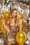 Portrait of blond young woman between golden balloons and ribbon