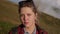 portrait of blonde blue-eyed young woman at nature at top of mount, closeup of face