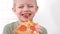 Portrait blonde boy Eating cheese Pizza Smiling close up .Happy Child chewing slice pizza Indoors. Unhealthy junk fast