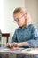 Portrait of blonde girl with big black glasses smiling happily while enjoying art and craft lesson in art school working together