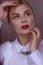 Portrait of a blonde girl with blonde hair in a white shirt in the studio room, with makeup and hairstyle, red lips and manicure,