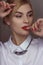 Portrait of a blonde girl with blonde hair in a white shirt in the studio room, with makeup and hairstyle, red lips and manicure,