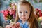 Portrait of a blonde girl in a blue dress. The child is sitting in the middle of a beautifully decorated room with vases and