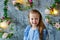 Portrait of a blonde girl in a blue dress. The child is sitting in the middle of a beautifully decorated room with vases and