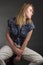 Portrait of blonde girl on a dark Studio background, he sits in the pose of Rodin`s thinker