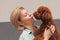 Portrait blonde woman hugging curly Toy poodle
