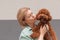 Portrait blonde woman hugging curly Toy poodle