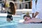 Portrait of a blonde woman lying belly down and receiving a massage near the pool