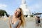 Portrait of blonde woman standing near white concrete statue of Buddha in Phuket.