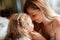 Portrait of blondes mother 30s and daughter 5 years. Beautiful mom gently touches child girl face at home. Loving