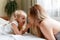 Portrait of blondes mother and daughter. Beautiful child girl gently touches the mother& x27;s face at home on bed. Loving