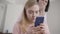 Portrait of blurred caucasian woman looking at smartphone screen over girl\'s shoulder with shocked facial expression