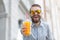 Portrait of a blurred stylish young hipster male with beard and mustache holding fresh orange juice in his hands