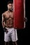Portrait, body and fitness man with punching bag in studio for training, challenge or power performance on black