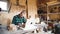 Portrait of bold moustache retired carpenter sitting at his workshop and working with laptop. Small business.