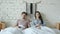 Portrait of bored couple watching TV changing channels in bed in loft style bedroom