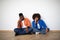 Portrait Of Bored Young Black Couple Sitting On Floor While Moving Home