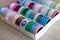 A portrait of a box full of colorful rolls of washi tape having different colors, patterns and textures. The tapes are ready to be